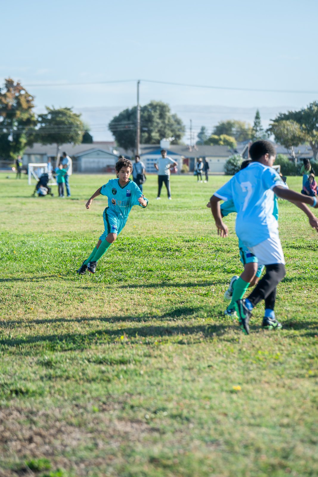 A player in teal turning away from a defender in light blue